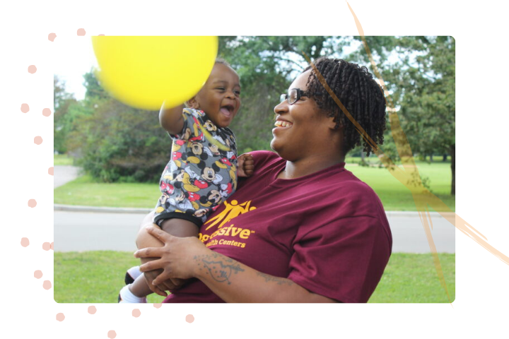 Woman smiling holding a baby and balloon