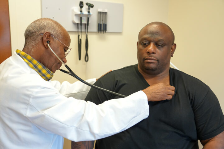 A picture of a doctor listening to a patient's heart with a stethoscope.